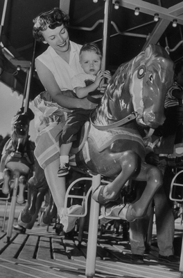 parent and child on merry-go-round horse b&w